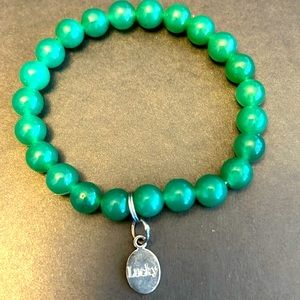 Green beaded stone bracelet with silver tone lucky charm, elastic.